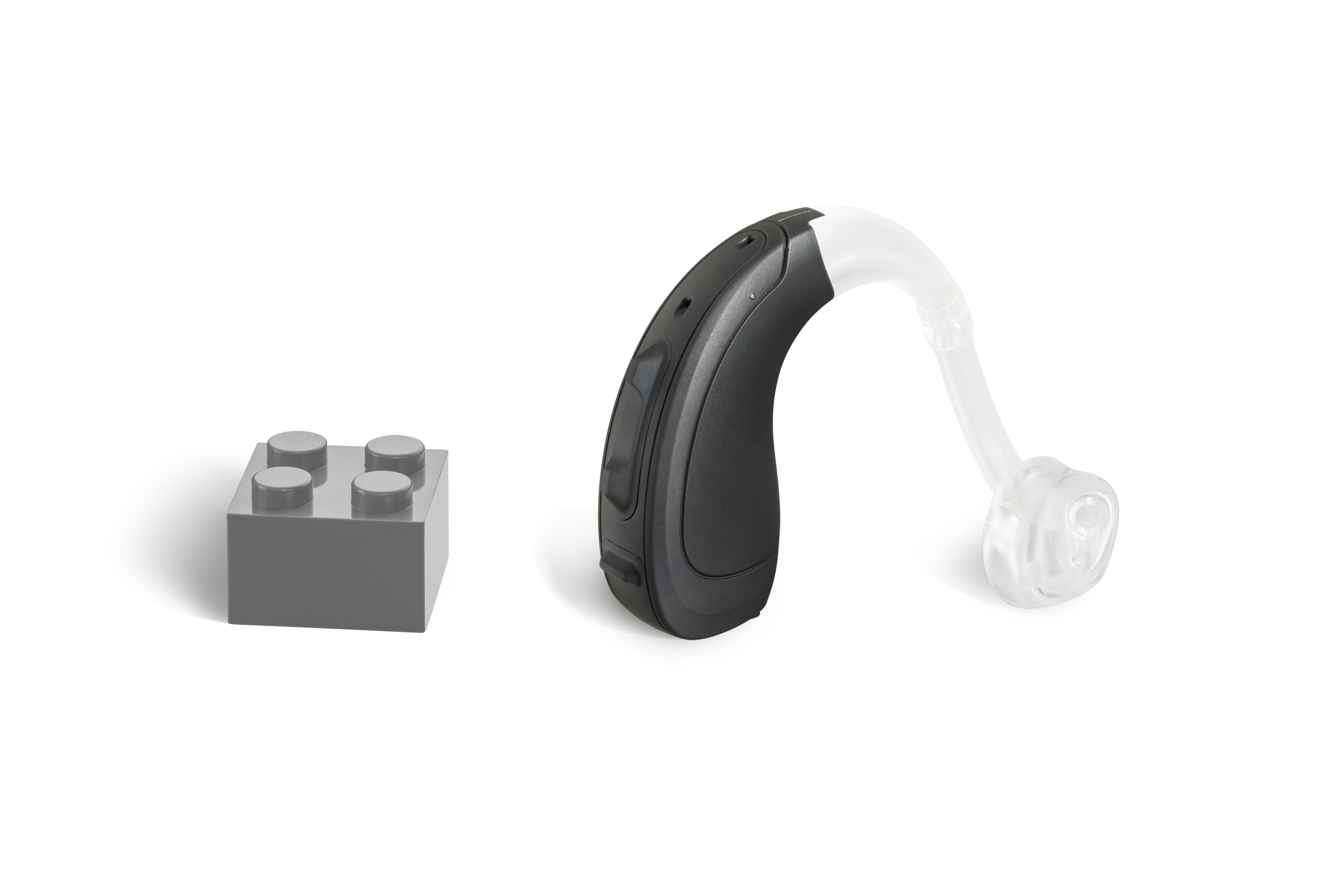 Das Hörgerät KINDwings 2200 als Bauform Hinter dem Ohr mit Energieversorgung Batterie neben einem grauen Klemmbaustein stehend auf weißem Hintergrund.