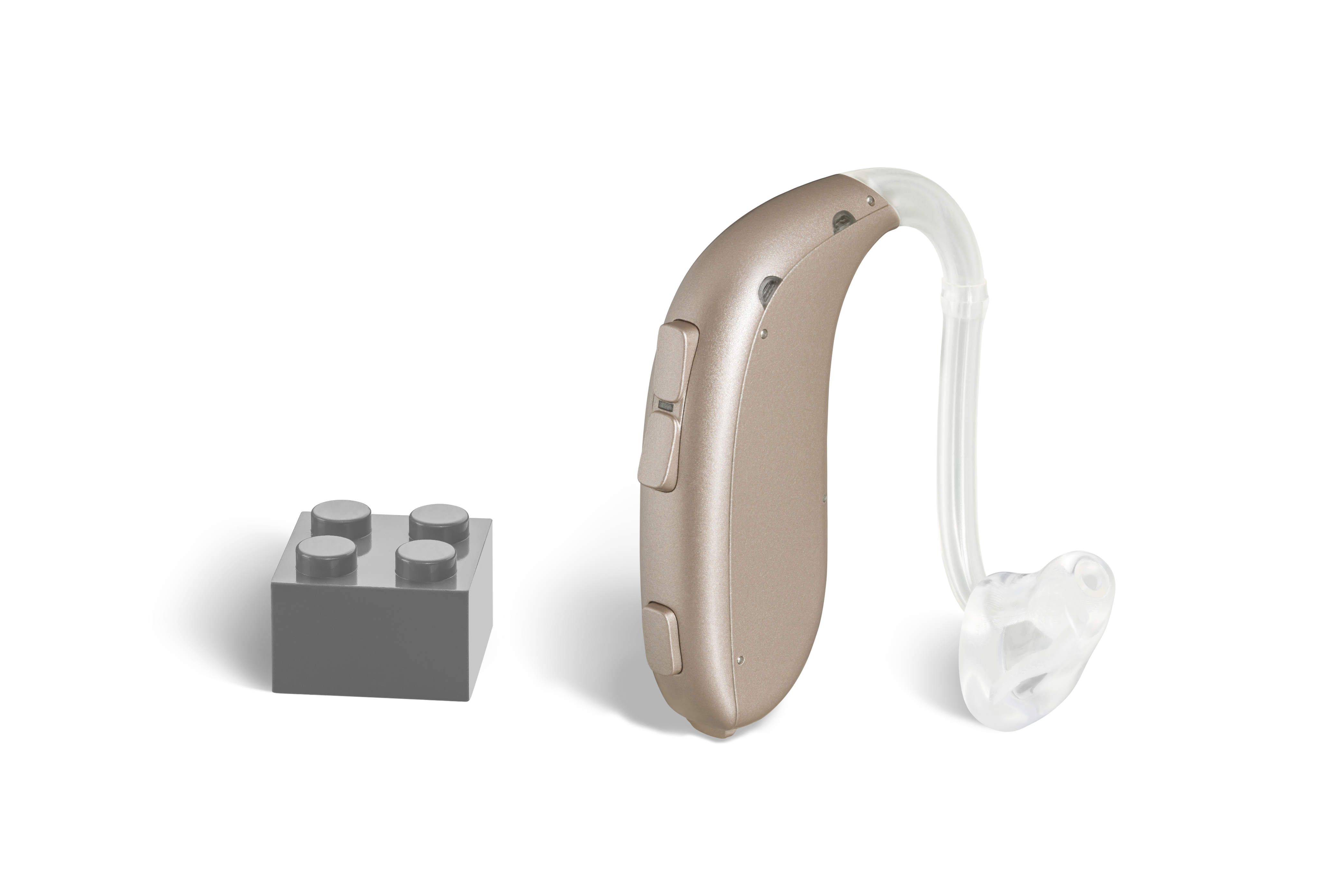 Das Hörgerät KINDduro 1110 (P) als Bauform Power HdO mit Energieversorgung Batterie neben einem grauen Klemmbaustein stehend auf weißem Hintergrund.