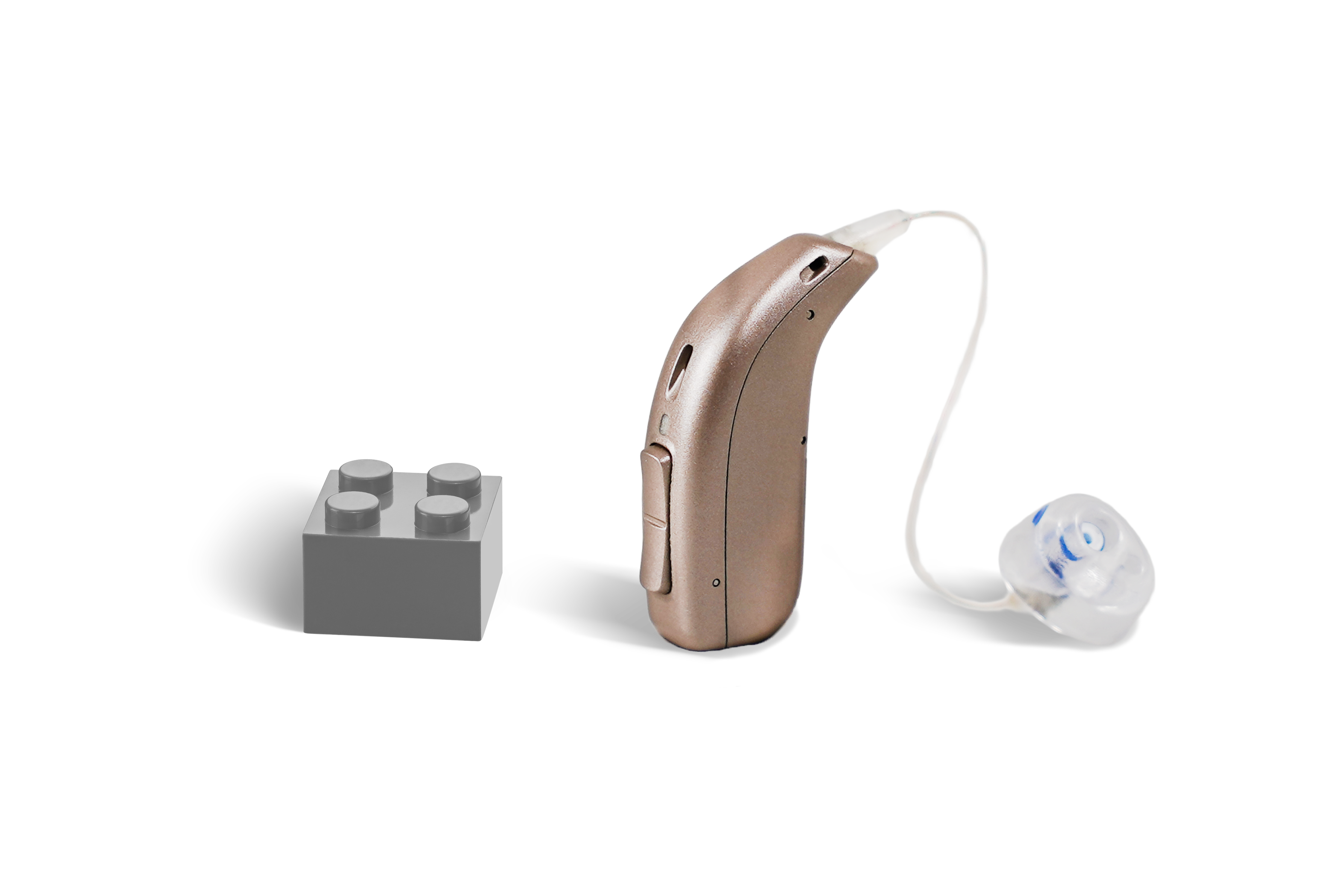 Das Hörgerät KINDsevan x 1 miniRITE C als Bauform HdO mit externem Hörer mit Energieversorgung Batterie neben einem grauen Klemmbaustein stehend auf weißem Hintergrund.