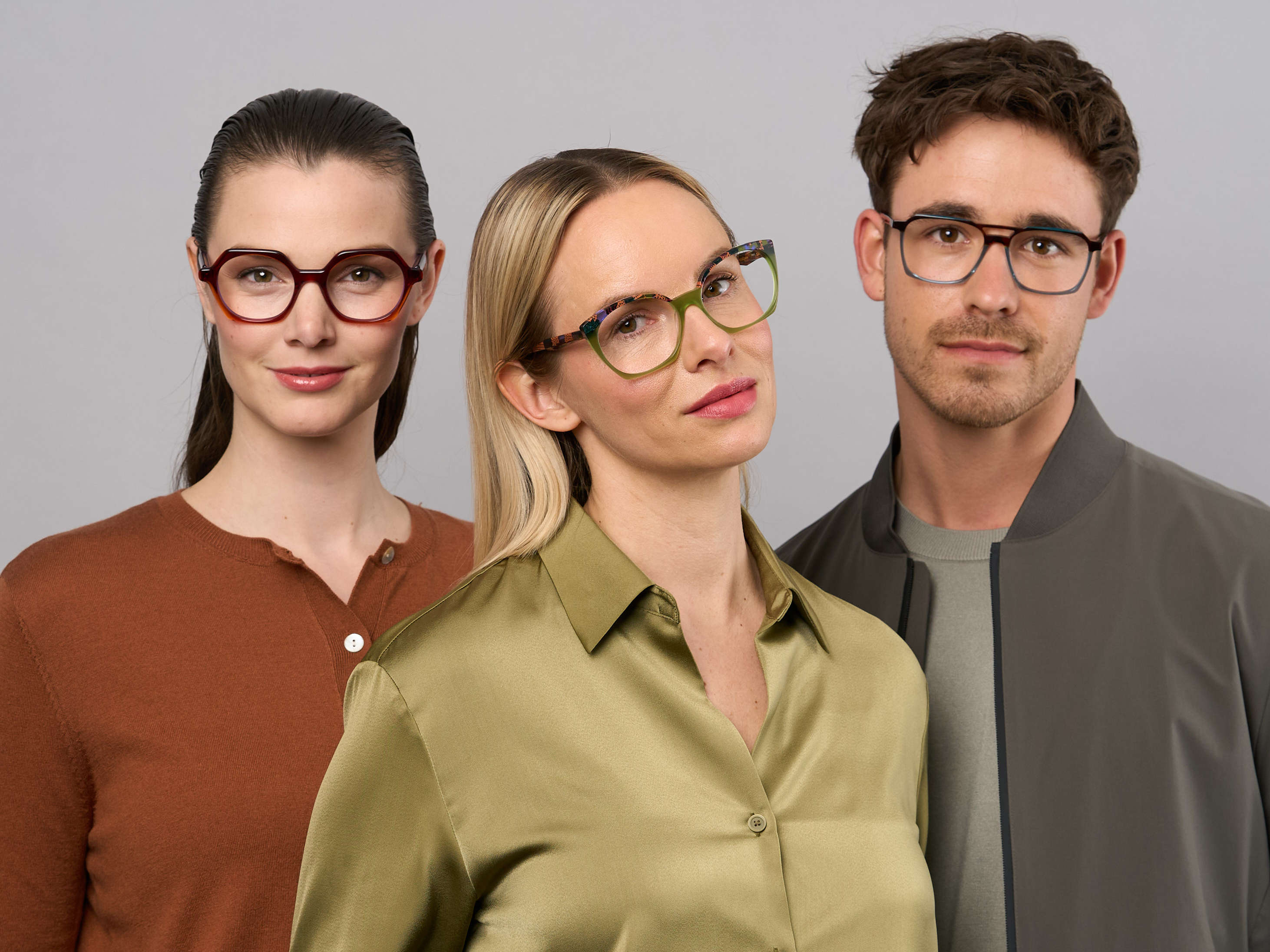 Zwei weibliche und ein männliches Model mit farbiger Kleidung und bunten Brillen. 