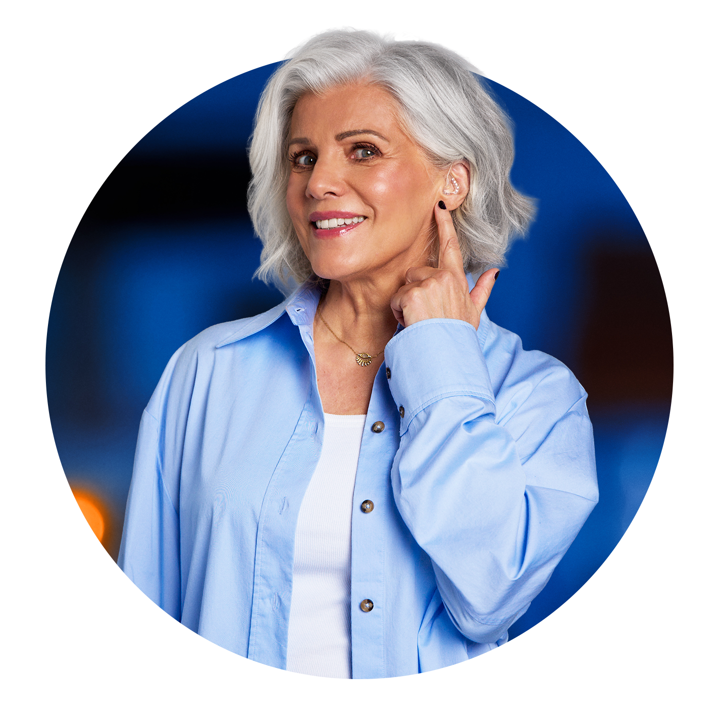 Kreisrundes Bild von Birgit Schrowange, die lächelt und mit der linken Hand auf ihr linkes Ohr zeigt.